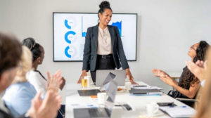 Business woman doing a presentation and being applaused by her colleagues