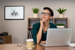 woman in front of a computer with her hand on her chin with a thinking face